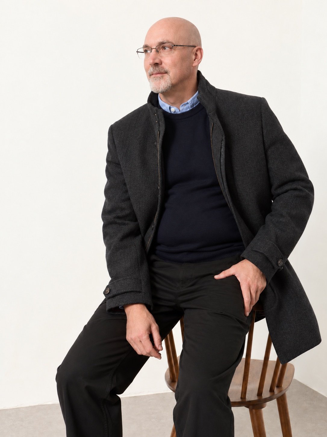 Brad Houser seated in a charcoal coat and navy sweater